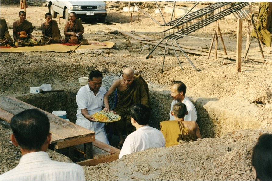 The groundbreaking ceremony for the sermon hall of 54.Wat Pa Mahachai Temple, Mahachai Sub-district, Pla Pak District, Nakhon Phanom Province, on January 9th, 1996. LP Kamphan placing auspicious items and blessings into the ground.